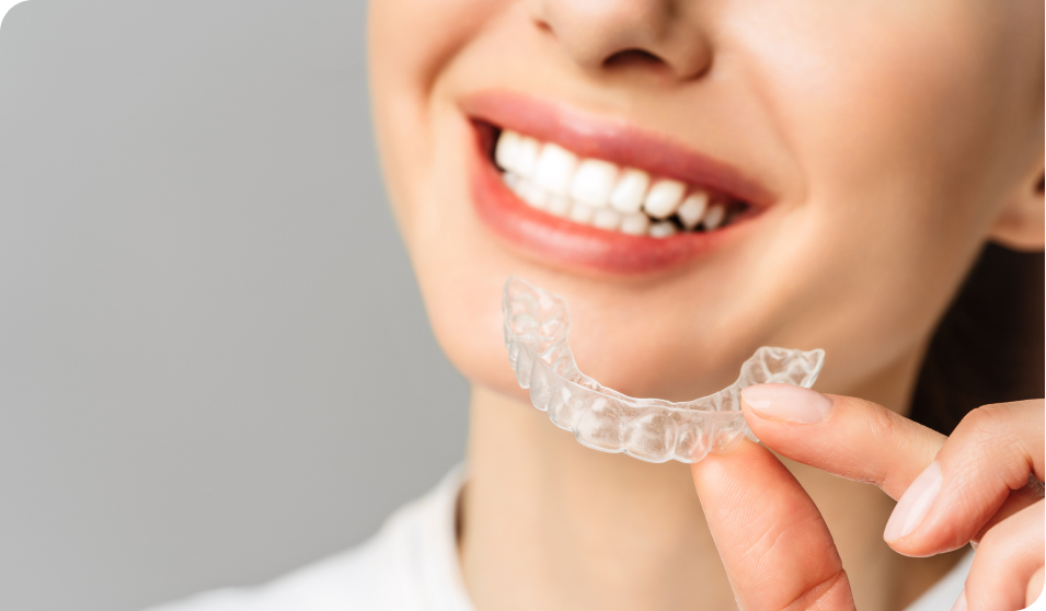 Smiling lady holding a transparent Invisalign aligner, illustrating Living Water Dentistry Offers Invisalign treatment in Surrey, BC