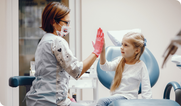 Doctor engaging with child patient with a friendly high-five gesture - Living Water Dentistry provides caring pediatric dental services in Surrey, BC